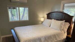 Una cama bien tendida con una colcha estampada, un cabecero de madera y una mesita de noche con una lámpara.