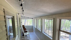 Una habitación larga y estrecha con mecedoras blancas y ventanas amplias.