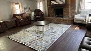 Una sala de estar acogedora con chimenea de piedra, sofás de cuero y una mesa de centro.