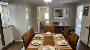 Un comedor con una mesa de madera dispuesta para seis personas, rodeada de sillas de madera.