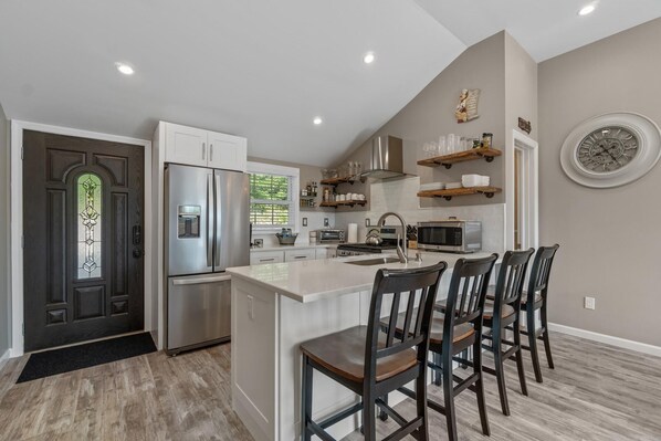 A modern kitchen with a central island, stainless steel appliances, and a dining area with four chairs.