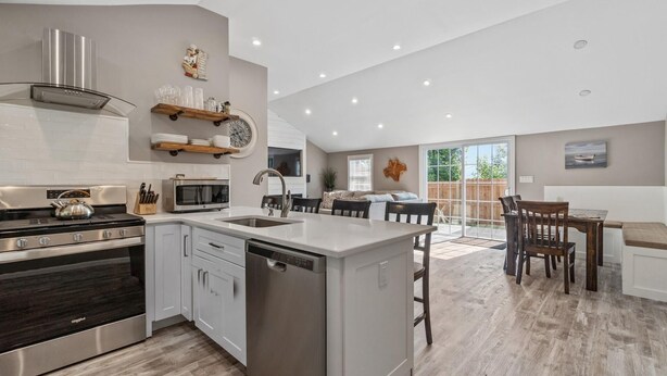 Una cocina moderna con una isla central, electrodomésticos de acero inoxidable y un comedor con mesa y sillas de madera.