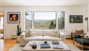 A living room with a sofa, coffee table, and a view of the outdoors.
