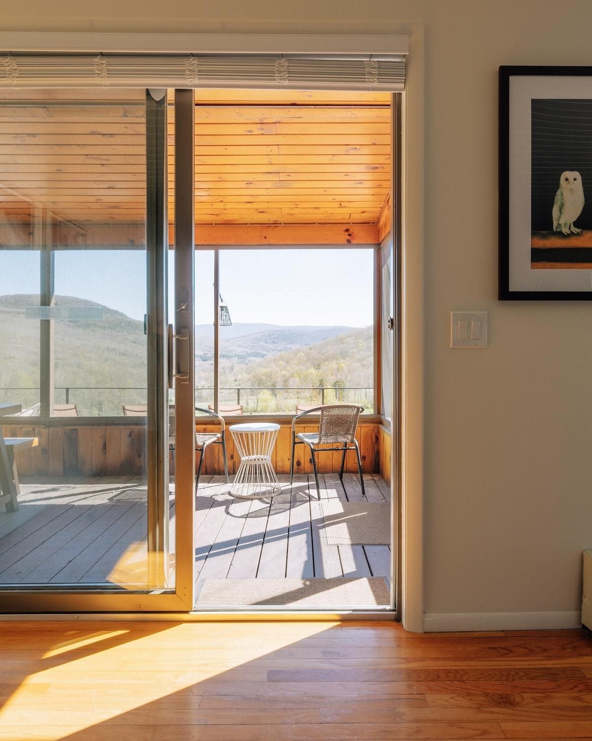 Una habitación con puerta de vidrio corredera que da a un patio exterior con vistas a un paisaje montañoso.