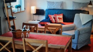 A cozy living room with a sofa, a television, and a table with chairs. - Apartment (Zislow)