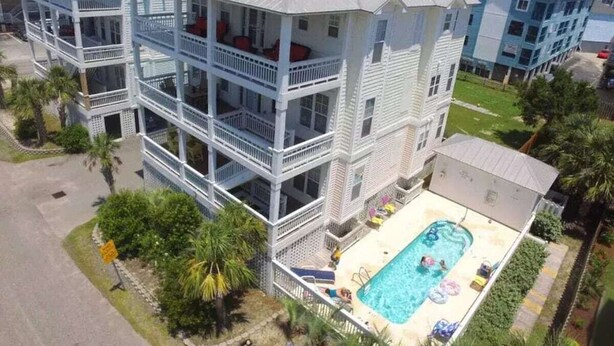 Ein mehrgeschossiges Hotel mit Balkonen, einem Pool und einem Parkplatz.