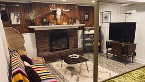 A cozy living room with a fireplace, a television, and a comfortable seating area. - Sweet little apartment with hot tub,gazebo,and an acre backyard! Walkable area! (Nashville)