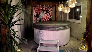 A hot tub with a wooden bench, surrounded by potted plants and hanging lights. - Sweet little apartment with hot tub,gazebo,and an acre backyard! Walkable area! (Nashville)