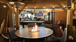 Ein Billardtisch mit Feuerstelle in der Mitte, umgeben von Korbstühlen.