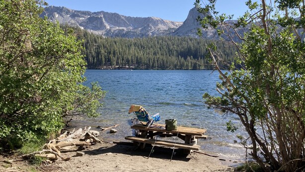 A lakeside picnic area with a bench and a cooler, surrounded by trees and mountains in the background. - Perfect Family & Dog Friendly 2 Story Condo, Sleeps 8+, 1 Mile To Village,  #66 (Mammoth Lakes)