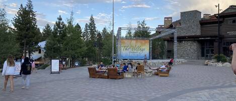 An outdoor seating area with a stage and a banner for 'The Village at Mammoth.'