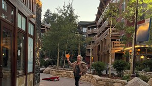 A ping pong table in an outdoor setting with stone walls and wooden buildings in the background.