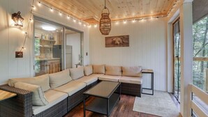 Un salon chaleureux avec un canapé d’angle, une petite table et un luminaire suspendu.