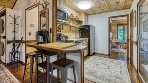 Une cuisine compacte agrémentée d’éléments en bois, dotée d’un îlot central et offrant une vue sur l’espace repas.