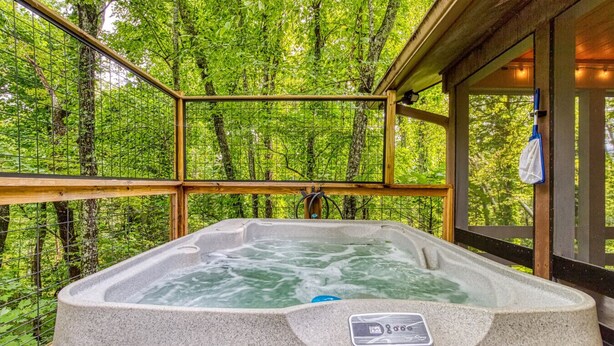 Un bain à remous dans un chalet en bois, entouré d’une forêt.