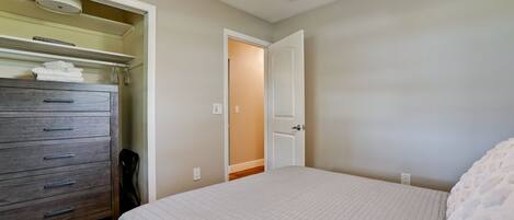 A bedroom with a bed, a dresser, and a door leading to another room.