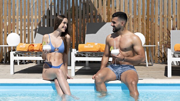 A poolside area with lounge chairs and a wooden fence in the background. - Lazy Days Adults Only Duna Parque Resorts & Hotels (Odemira)