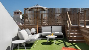 A rooftop patio with a white sofa, a small round table, and a wooden staircase. - Lazy Days Adults Only Duna Parque Resorts & Hotels (Odemira)