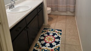 A bathroom with a sink, mirror, toilet, and striped shower curtain. - Single Family Home 3 bedroom 2 bath (San Angelo)