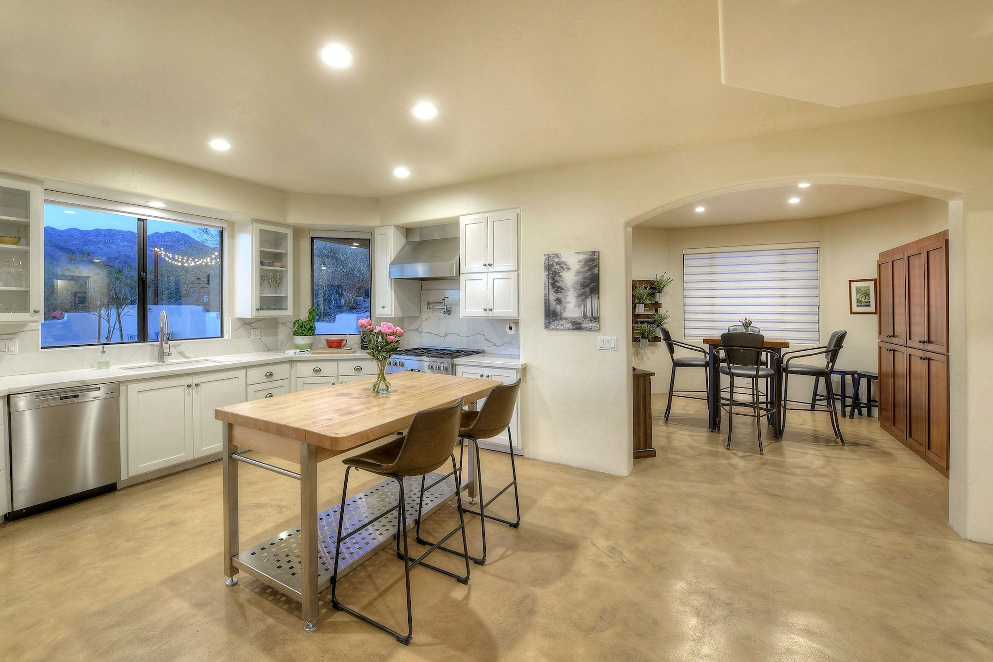 A modern kitchen with white cabinets, stainless steel appliances, and a wooden island with bar stools.