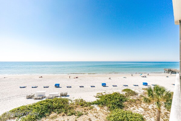 Relax on the beach with lounge chairs and umbrellas, and enjoy the pier extending into the calm waters.