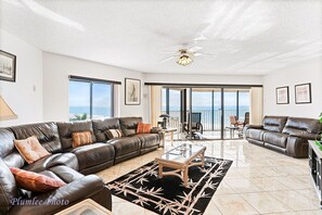 Relax in this stylish living room with a leather sofa, glass coffee table, and sliding glass door leading to a balcony with ocean views.