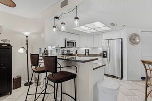 A modern kitchen with white cabinets, stainless steel appliances, and a central island with bar stools.
