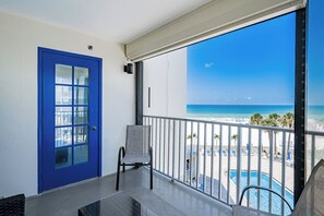 Un balcon avec une porte bleue, une chaise et une vue sur la piscine.