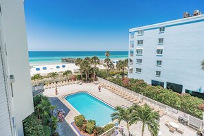 A hotel with a pool, beach view, and outdoor seating area. - Beach Palms 310 - GULF VIEW Condo! (Indian Shores)