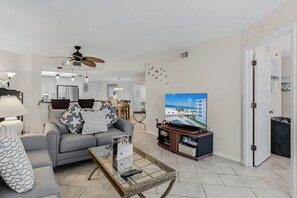 A living room with a sofa, coffee table, TV, and ceiling fan.