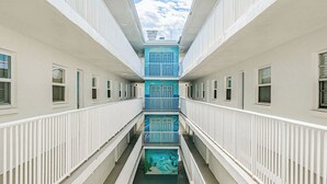Ein mehrgeschossiges Entree mit weißen Geländern und einem zentralen Atrium, das ein Wandgemälde zeigt.