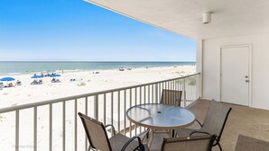 Un balcon donnant sur une plage, une table ronde et des chaises.