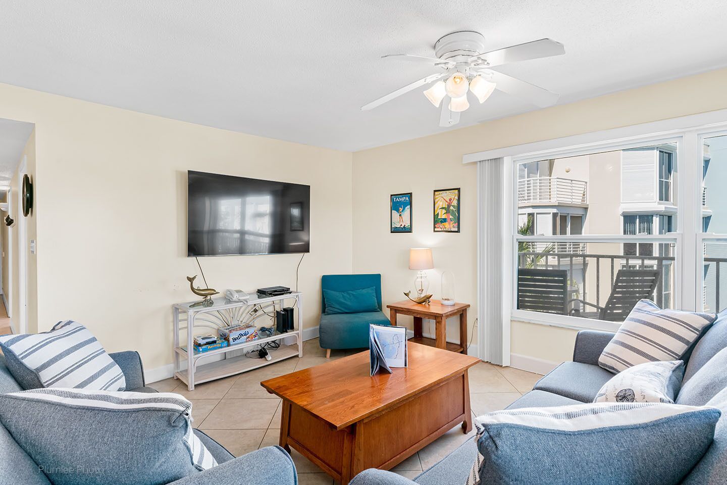A living room with a flat-screen TV, a ceiling fan, a wooden coffee table, and a sofa set.