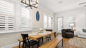 A dining area with a wooden table, black chairs, and a bench. There are white walls and a chandelier. - Fall Rates! | Pool | Foosball | Dog Friendly (Mexico Beach)