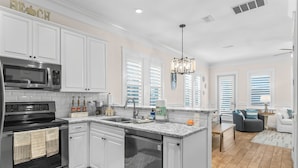 A modern kitchen with white cabinetry, a built-in microwave, and a dishwasher. - Fall Rates! | Pool | Foosball | Dog Friendly (Mexico Beach)