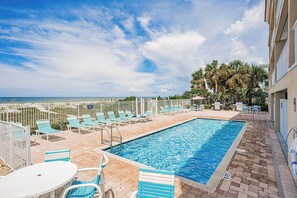 A swimming pool with lounge chairs and a view of the ocean.