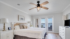 A bedroom with a bed, bedside tables, a ceiling fan, a dresser, and a television. - Ohana House 333 - Intercoastal Views with a Pool (Indian Rocks Beach)