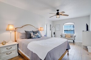 A bedroom with a bed, nightstands, a ceiling fan, a window, and a view of the outdoors. - Ohana House 333 - Intercoastal Views with a Pool (Indian Rocks Beach)
