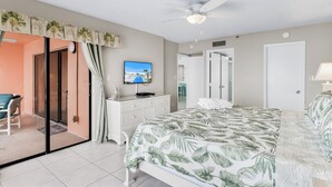 A bedroom with a bed, a television, a ceiling fan, and a sliding glass door leading to an outdoor area. - Gulf-Front 3BR | Pool & Sunsets | Reef Club 310 (Indian Rocks Beach)