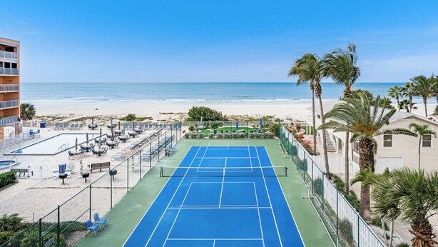 A tennis court with a view of the beach and ocean. - Gulf-Front 3BR | Pool & Sunsets | Reef Club 310 (Indian Rocks Beach)