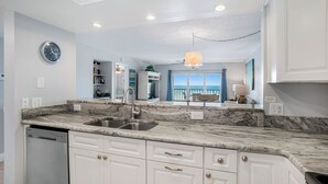 A modern kitchen with marble countertops, a double sink, and white cabinetry.