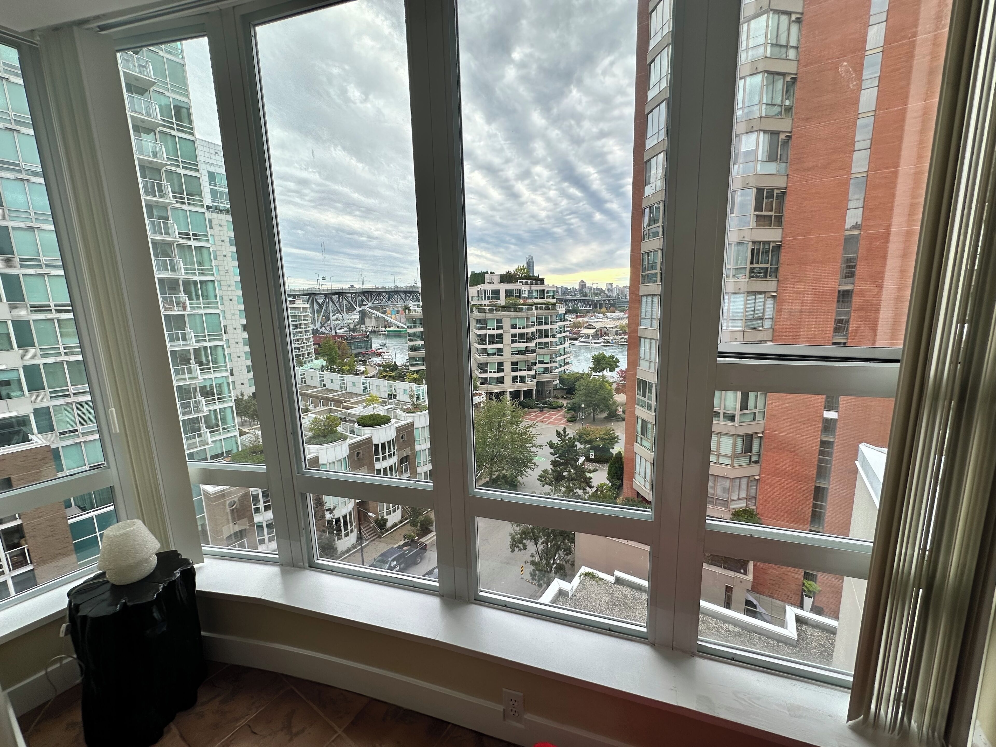 Un apartamento moderno en un rascacielos con grandes ventanales que dan a una vista panorámica de la ciudad, incluyendo un puente y un río.