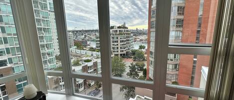 Un apartamento moderno en un rascacielos con grandes ventanales que dan a una vista panorámica de la ciudad, incluyendo un puente y un río.