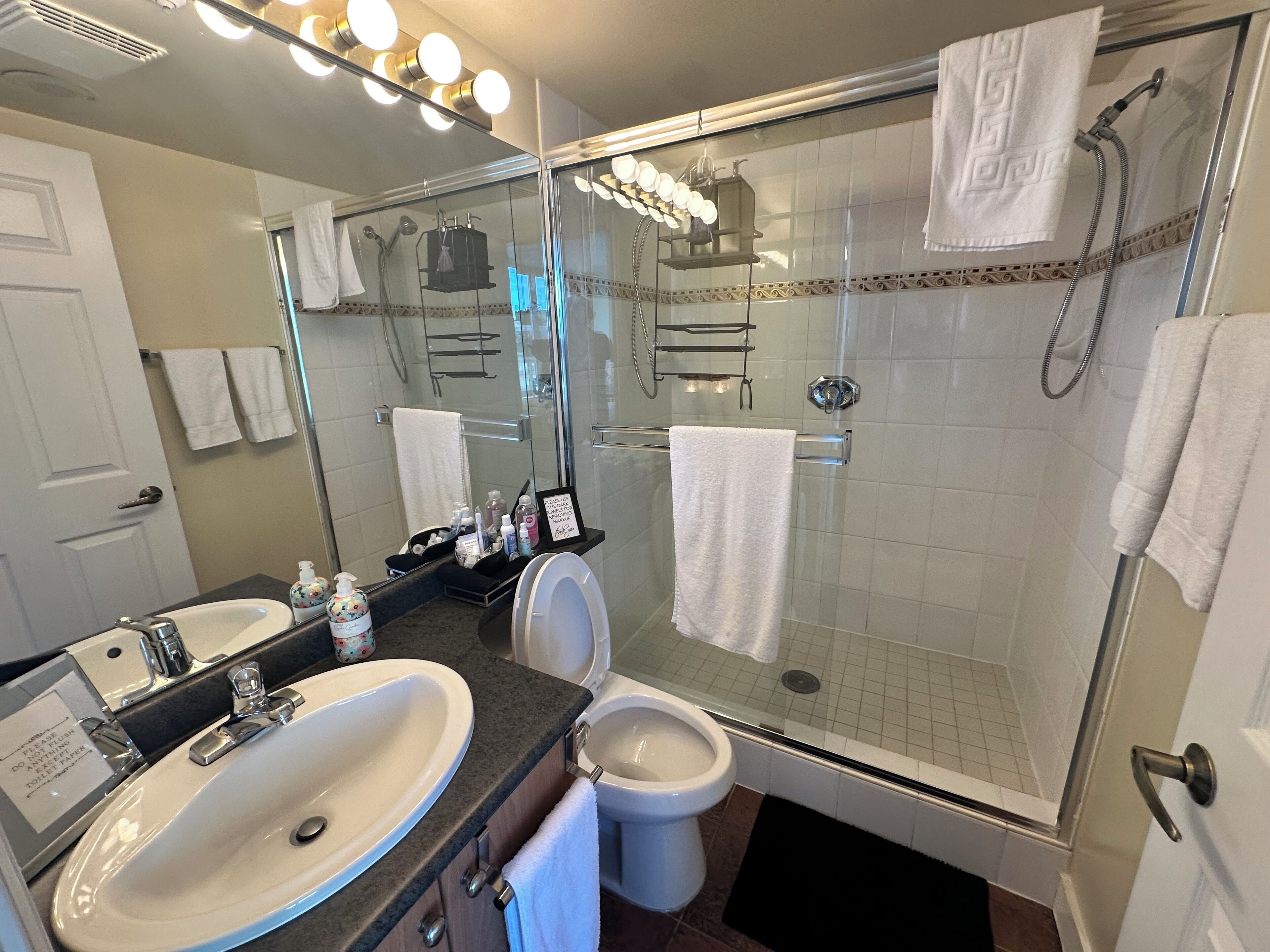 A modern bathroom with a glass-enclosed shower, a sink, and a toilet.