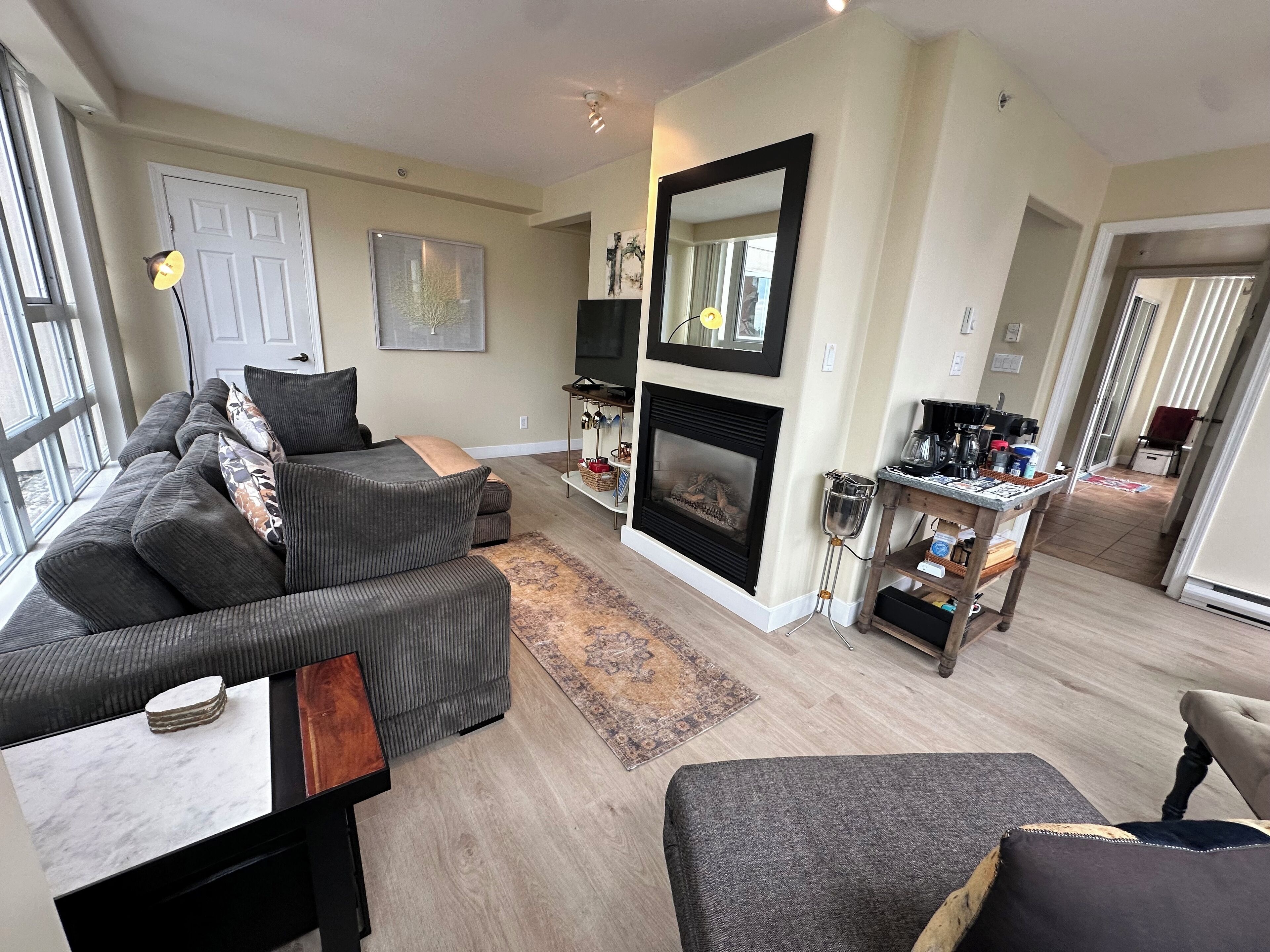 A living room with a grey sofa, a fireplace, a coffee table, and a TV.