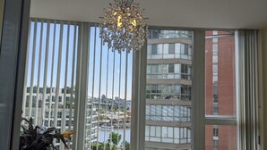 Une pièce dotée de grandes fenêtres, d’un lustre et offrant une vue sur le paysage urbain.
