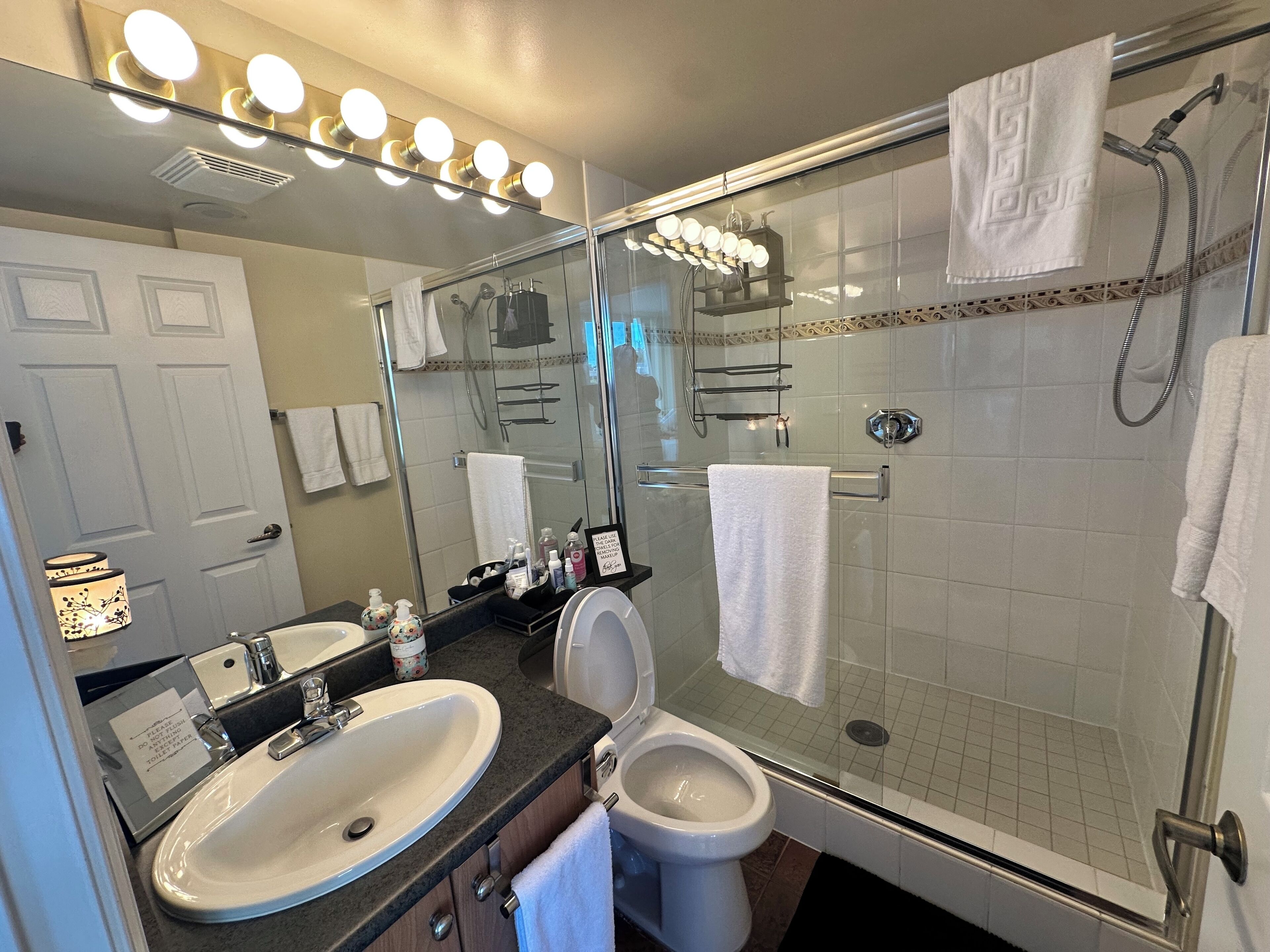 A modern bathroom with a glass-enclosed shower, a sink, and a toilet.