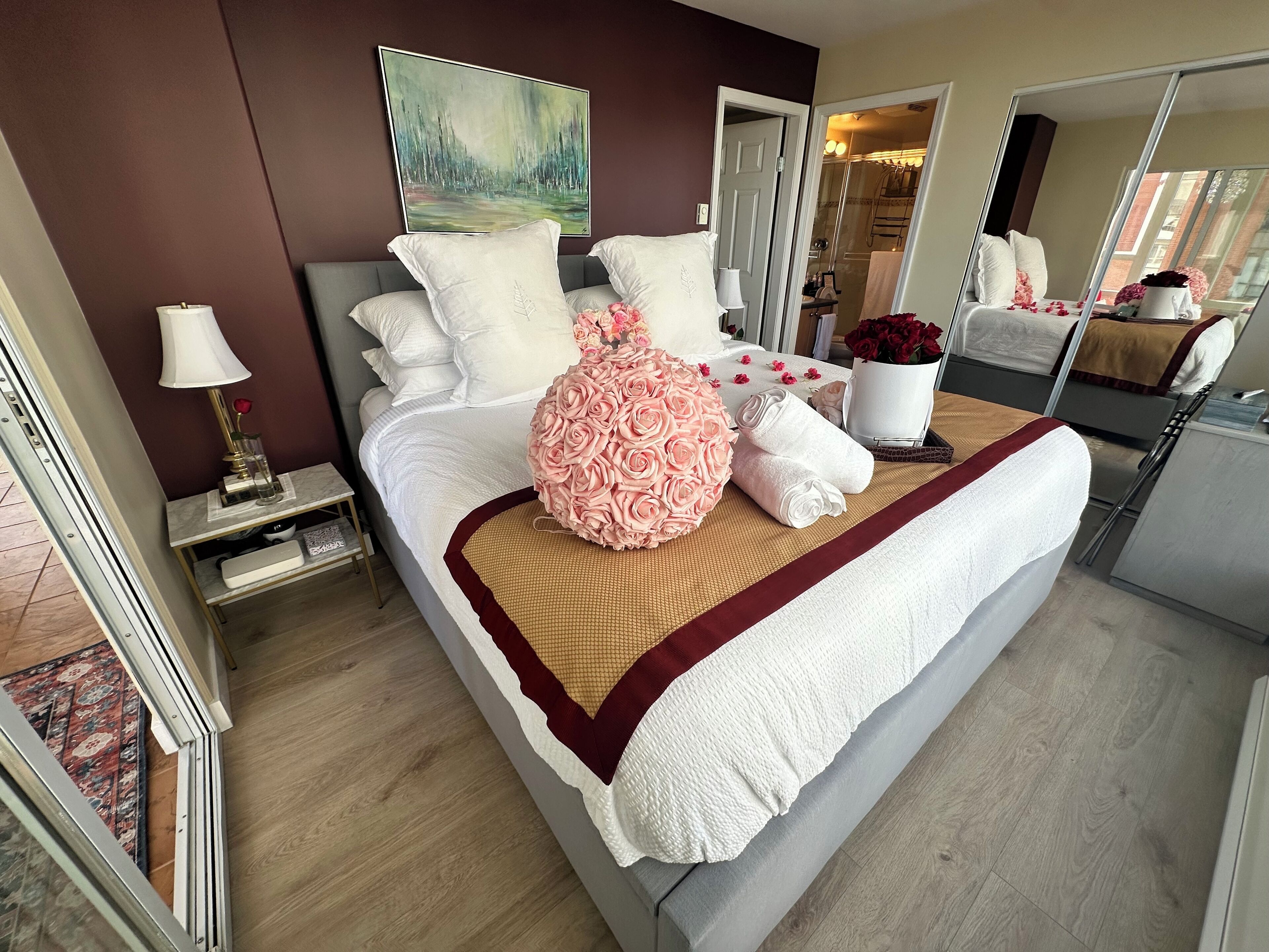 Une chambre d’hôtel bien aménagée, dotée d’un grand lit, d’une table de chevet avec une lampe, d’un miroir et offrant une vue sur la salle de bain.