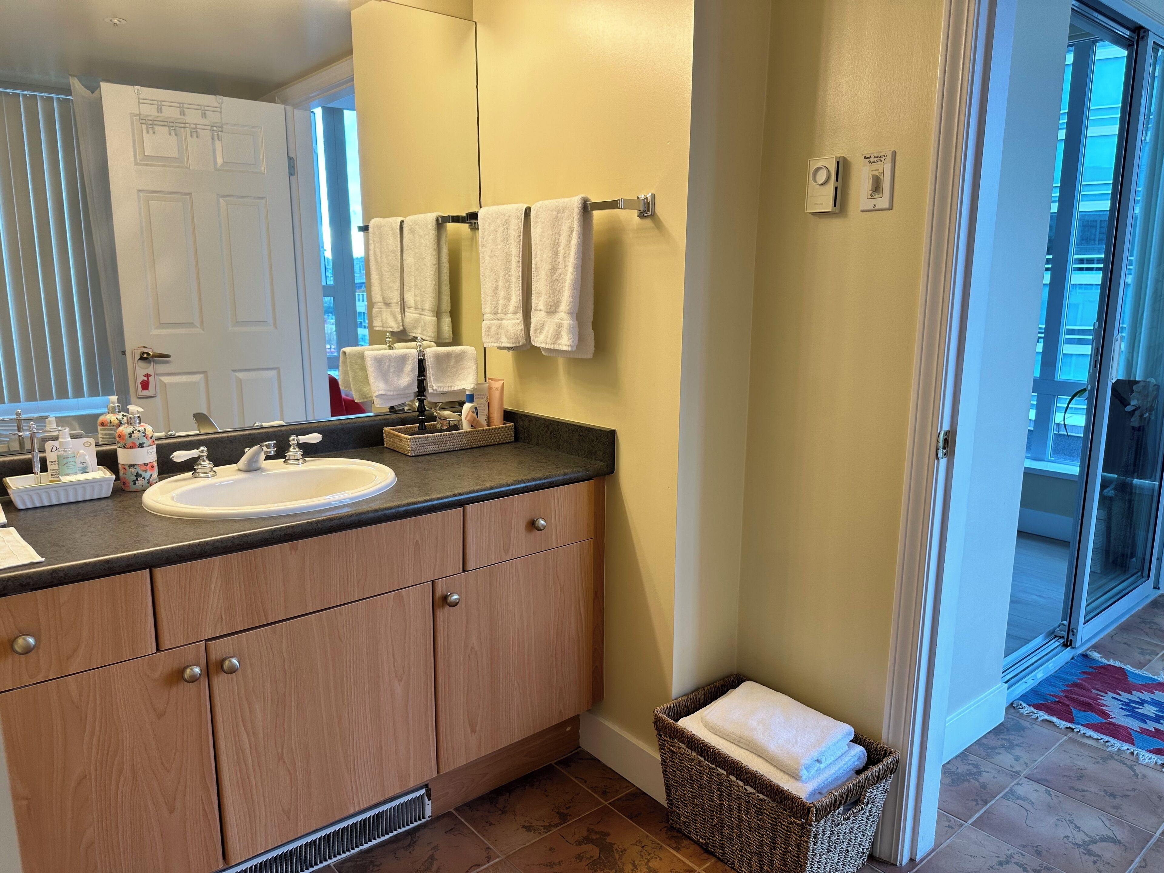 A bathroom with a sink, mirror, wooden cabinets, and a towel rack.