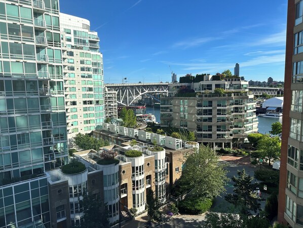 A high-rise building with multiple balconies and a view of a river with a bridge in the background.